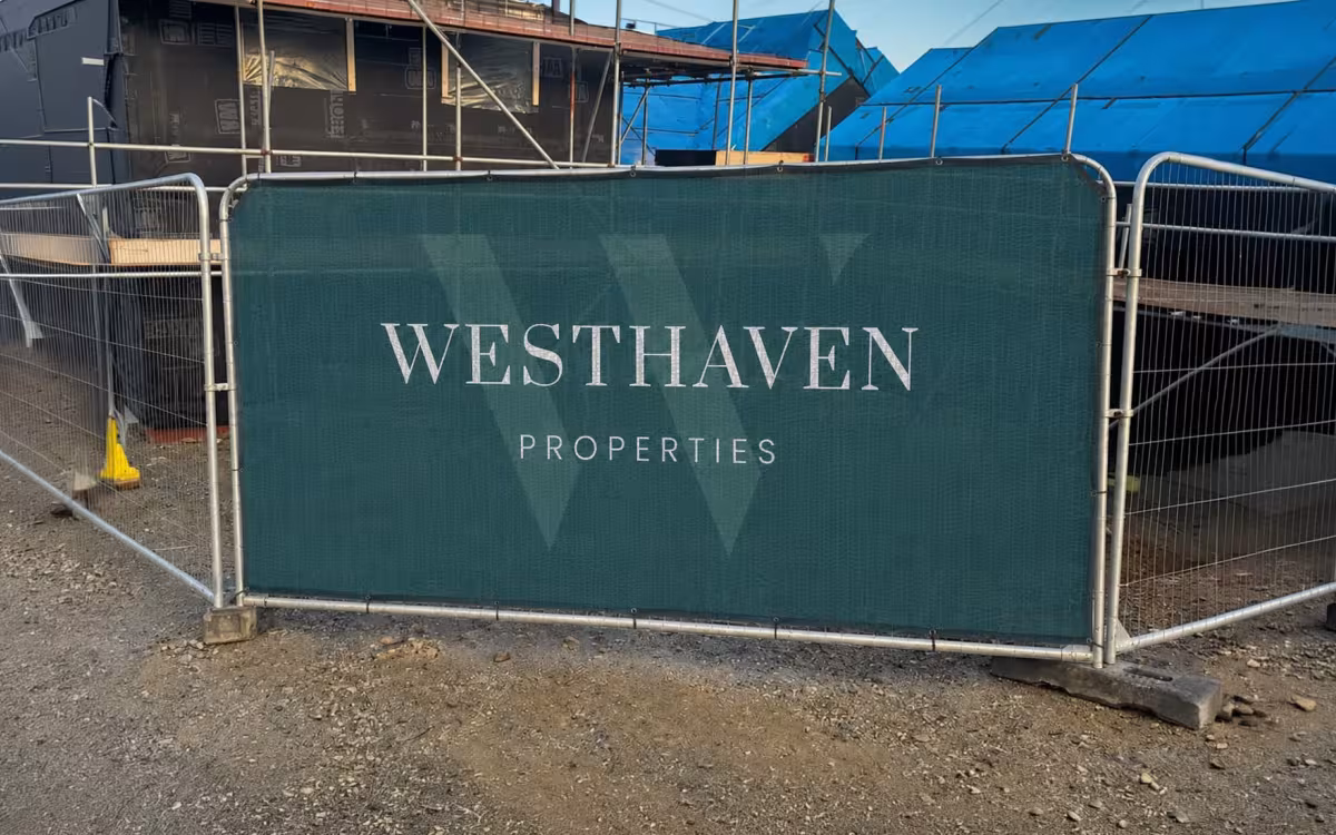 Printed PVC mesh Heras fence cover with property developer branding fitted to temporary fencing around a construction site.